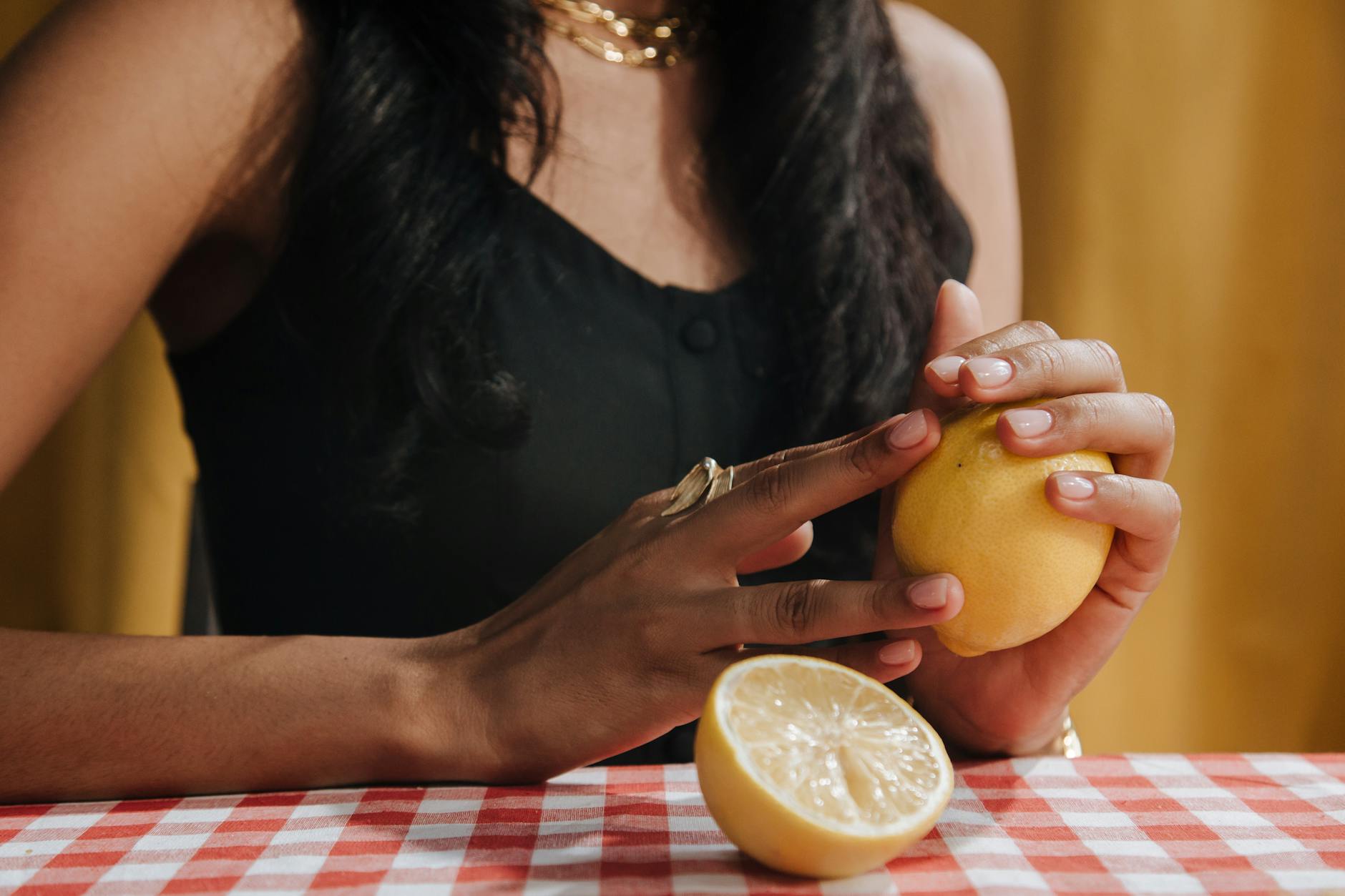 Woman holding a fresh lemon at a dining table, symbolizing natural vitality and wellness