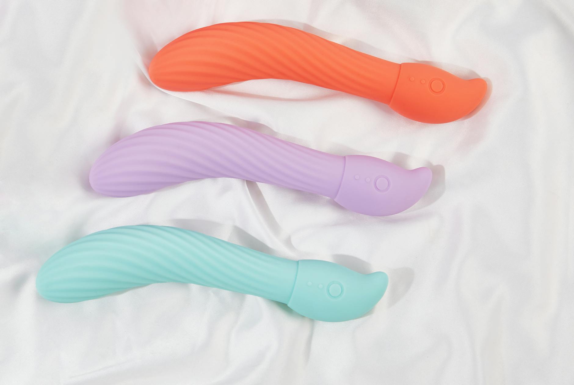 Three smooth silicone vibrators arranged on white fabric, ready for partner exploration