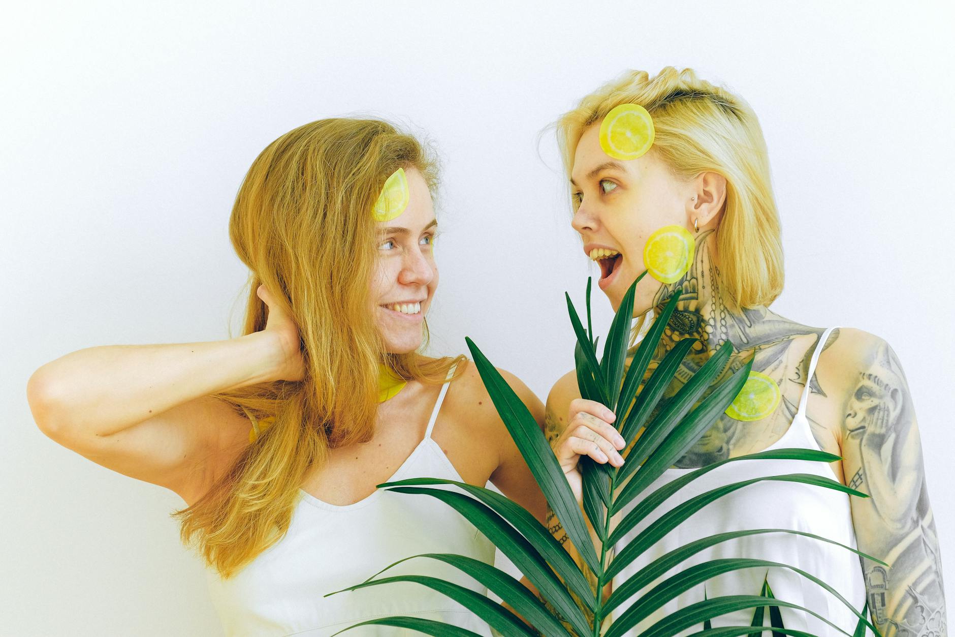 Dos mujeres sonrientes con rodajas de limón, expresando alegría y diversión en un ambiente interior