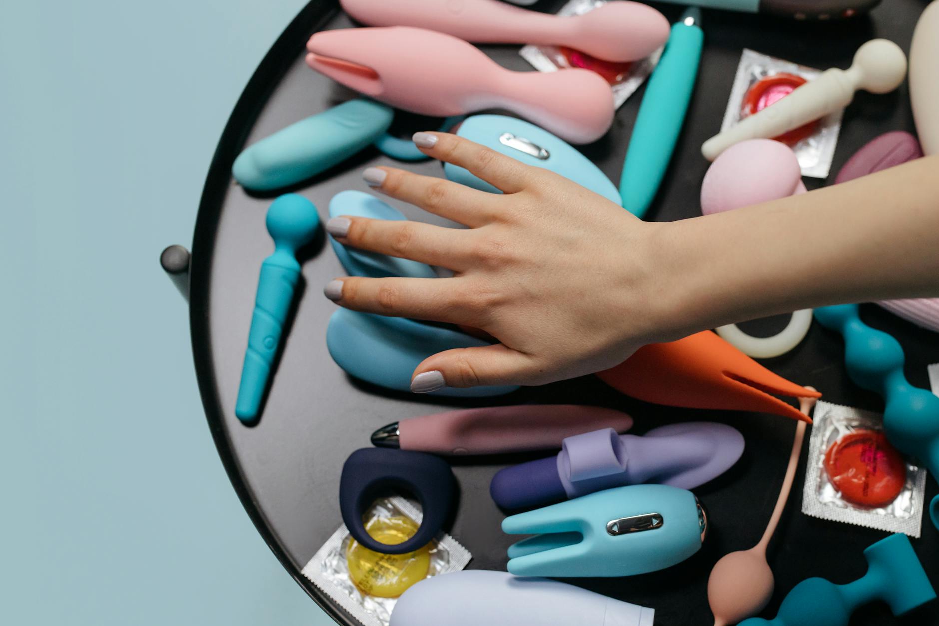 Mano sosteniendo un vibrador azul oscuro contra un fondo púrpura minimalista