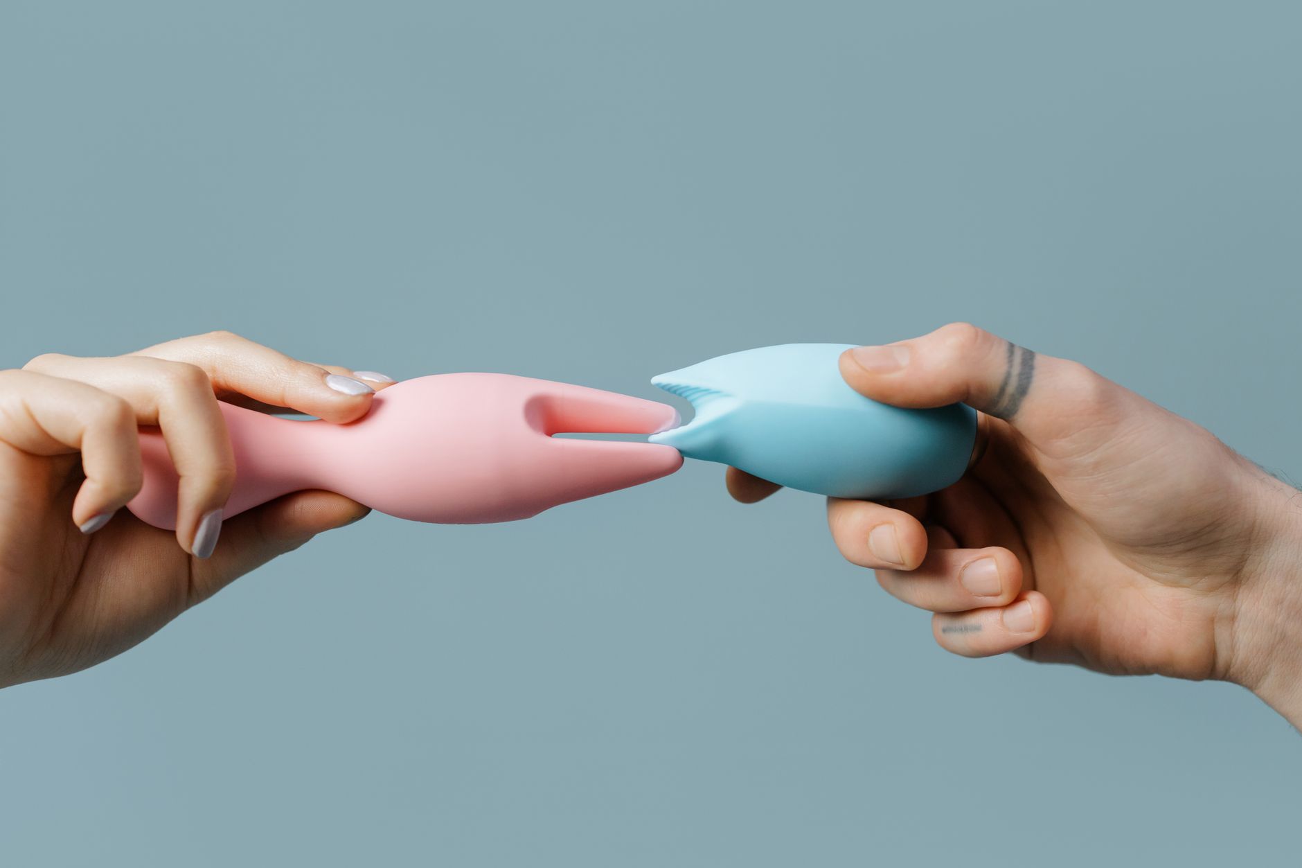 Manos sosteniendo juguetes de silicona pastel, perfectos para temas de placer y bienestar