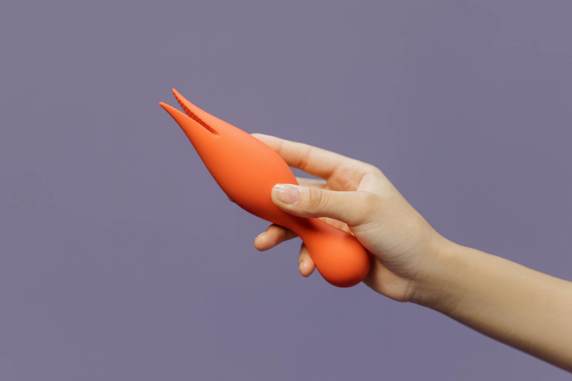 Hand holding a colorful vibrator against a minimalistic background, symbolizing intentional choice