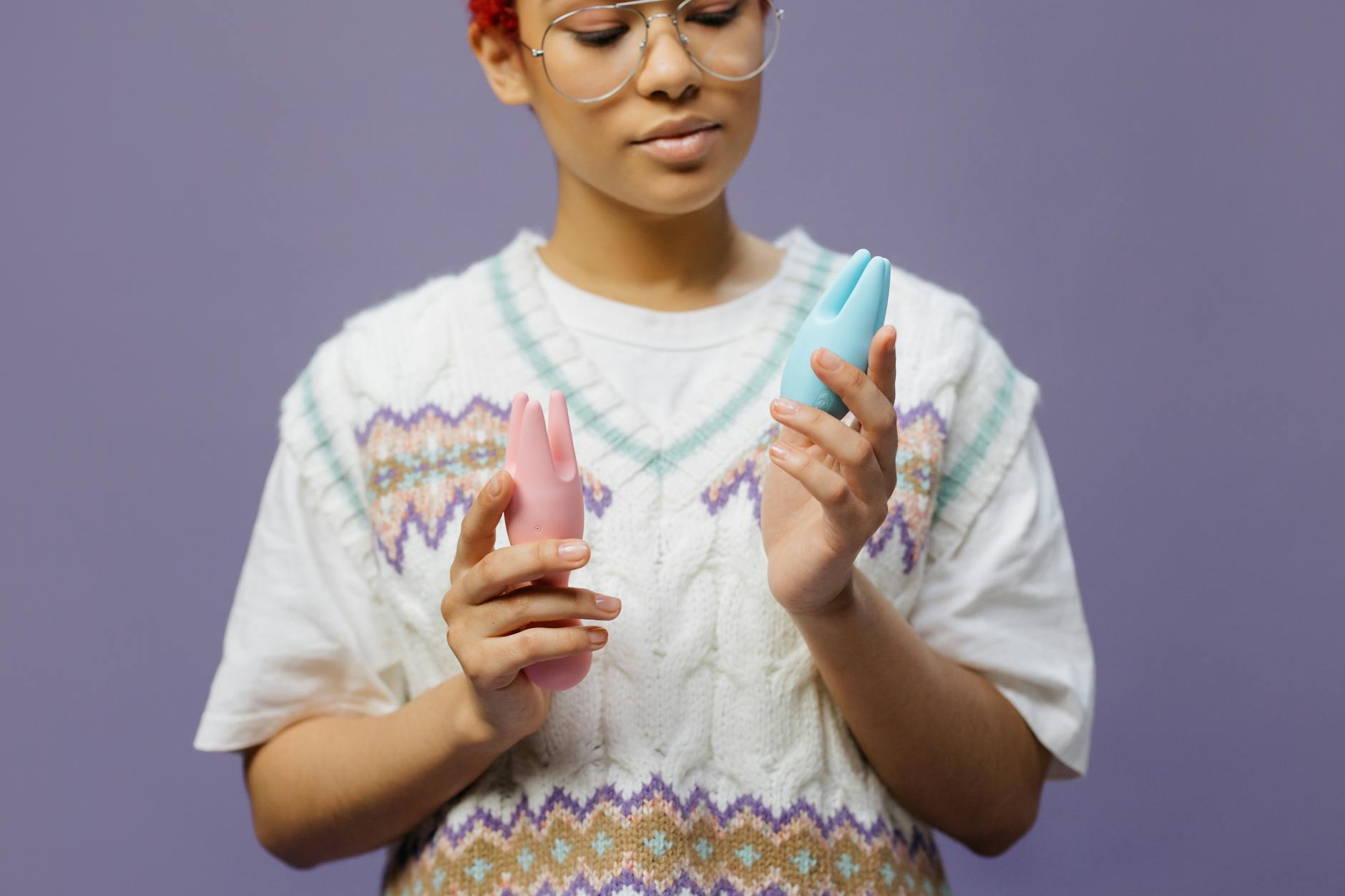 Woman holding a blue clitoral vibrator in contemplative consideration