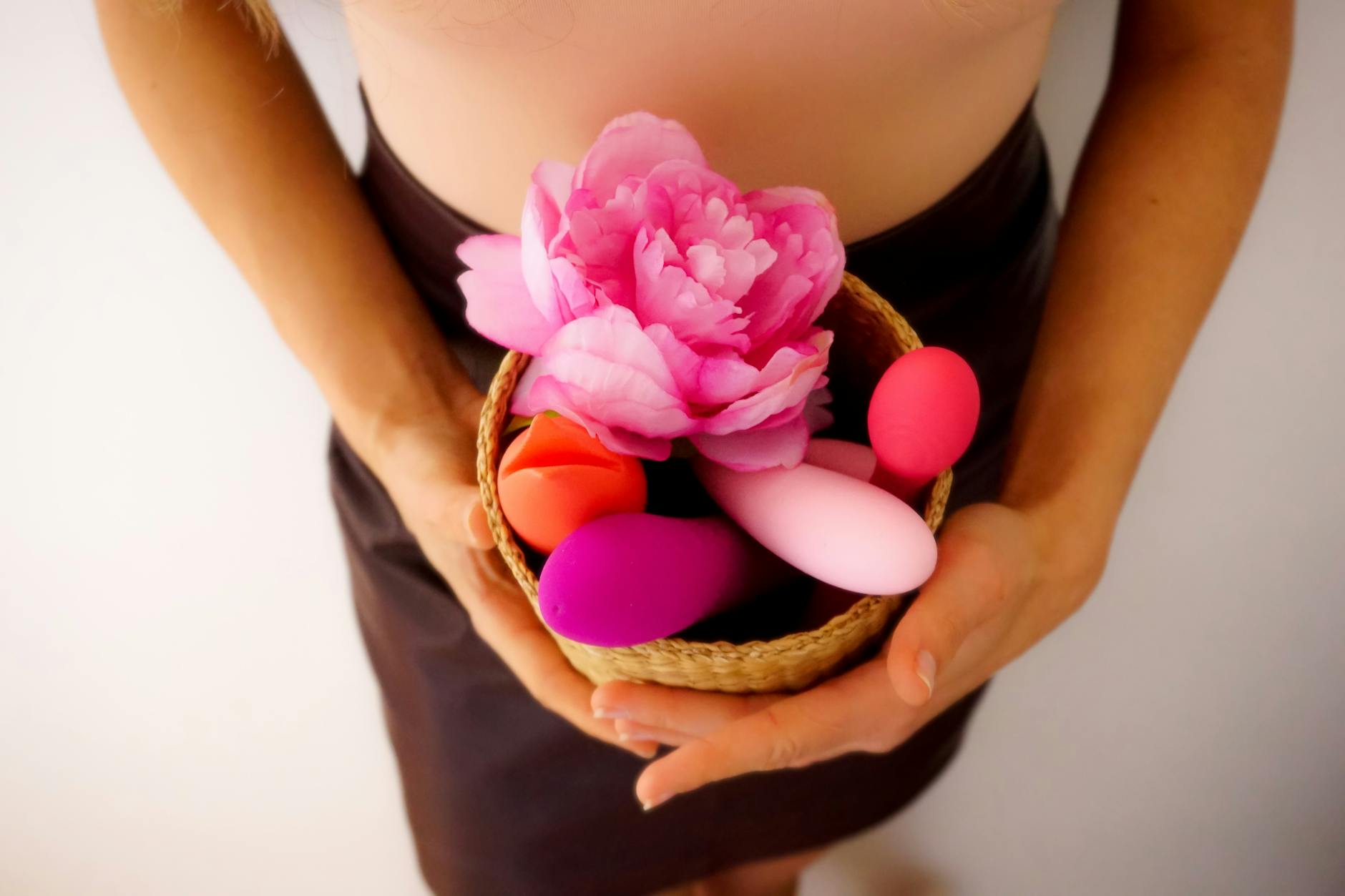 Cesta con vibradores de colores y flor rosa, representando los vibradores de limón de Hellanancylemon