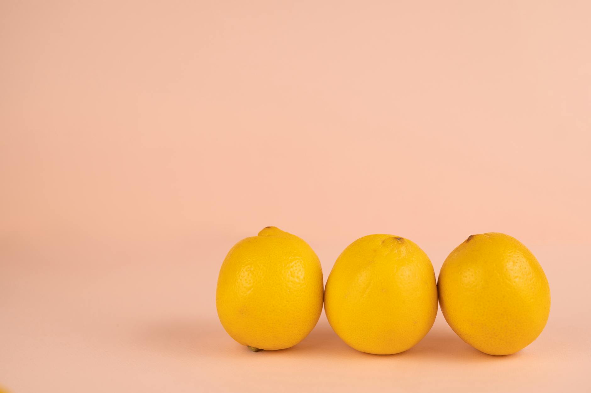 Hand holding a lemon clitoral vibrator against a minimalist purple backdrop